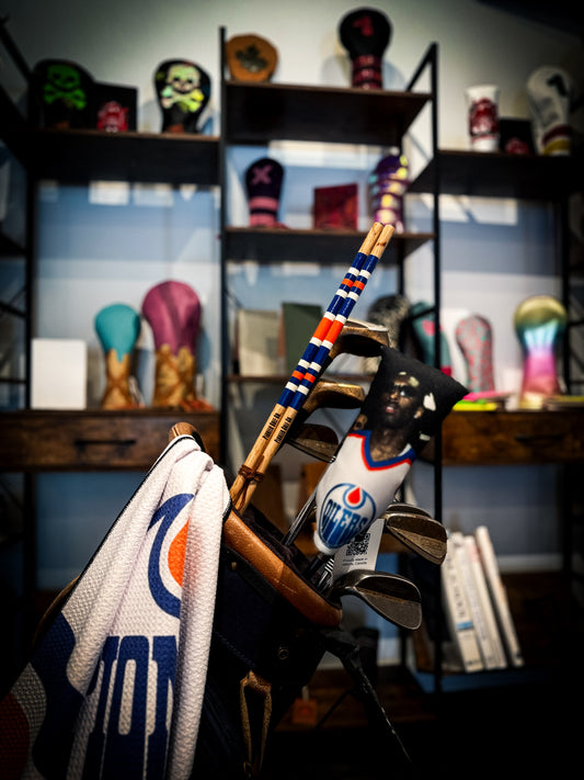 Golf club with colorful design in front of a shelf with various items