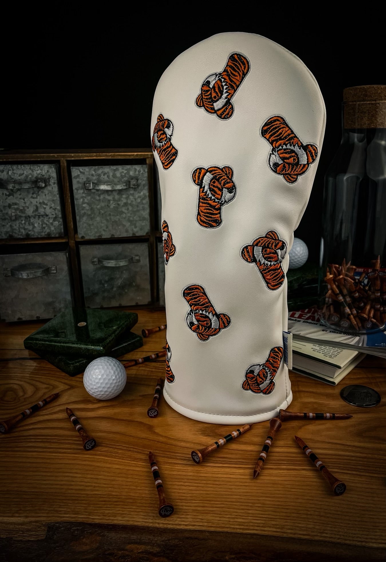 A set of golf club head covers with a tiger-themed design, displayed on a wooden surface. The covers are primarily green with yellow and white accents, featuring the text 'Pride' and tiger graphics.